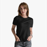 A woman wearing a black organic cotton tee and light blue jeans.