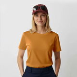 Woman wearing a mustard yellow t-shirt and maroon cap with sunglasses on a plain background