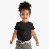 A girl wearing a black blank organic cotton t-shirt and beige pants standing against a white background.