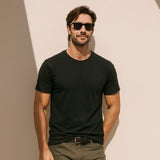 Man wearing a black t-shirt and sunglasses against a beige wall