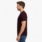 Man wearing a dark red t-shirt and blue jeans on a white background