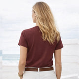 Woman wearing a maroon t-shirt with a blurred beach background