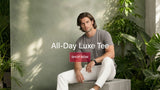 Man sitting outdoors with promotional text for 'All-Day Luxe Tee' and 'Shop Now' button.