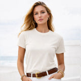 Woman wearing a white t-shirt with a blurred beach background