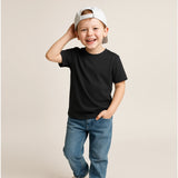 Child wearing a black t-shirt, blue jeans, and a white cap on a beige background