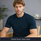 Man wearing a navy blue t-shirt sitting in a room with a neutral background