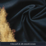 Navy blue fabric with a textured surface and dried plant on a dark background