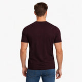 Man wearing a dark brown t-shirt and blue jeans on a white background