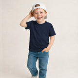 Child wearing a navy t-shirt and blue jeans with a white cap on a beige background